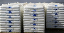 Three stacks of white sacks with blue labels.
